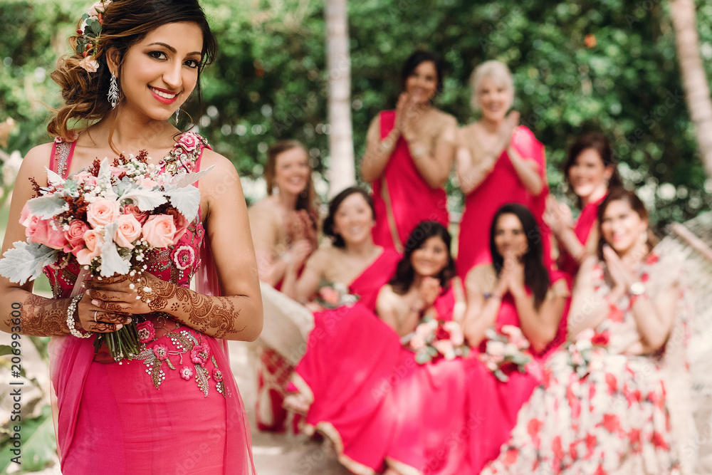 Indian bridesmaids admire beautiful bride posing together in the garden Indian bridesmaids admire beautiful bride posing together in the garden