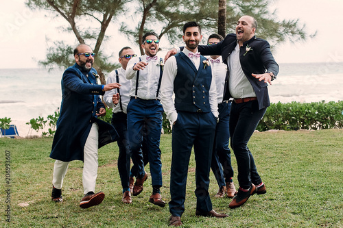 Handsome Indian groom and groomsmen in classy suits pose together on the lawn