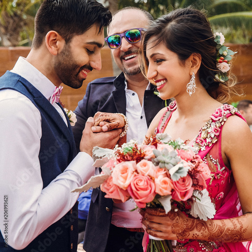 Happy Hindu groom holds tender bride's hand during the ceremony photo