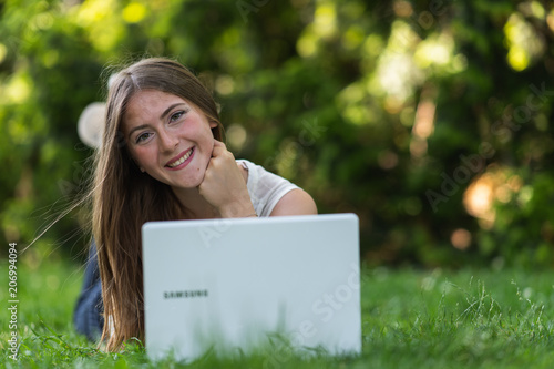 Young dark blonde girl studying in a park with a laptop