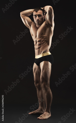 Man shows strong body and muscles at black background