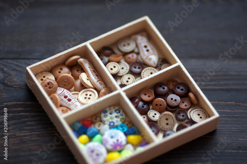 Different colorful decorative clothes buttons in a wooden box