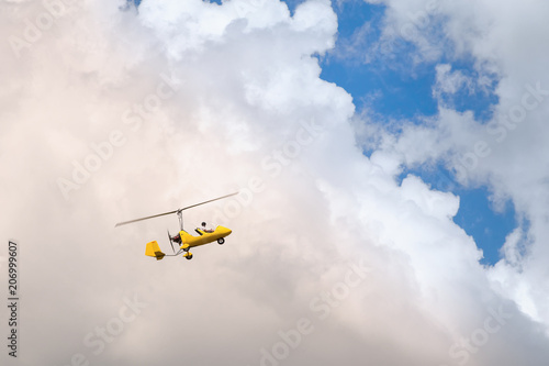 Small helicopter for two person flying on the cloudy sky