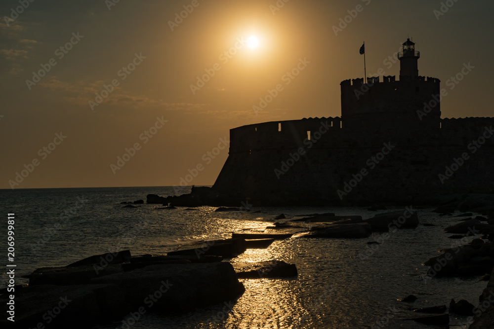 St. Nicoaus fortress with lighthouse in Mandraki harbor in City of Rhodes, sunset (Rhodes, Greece)