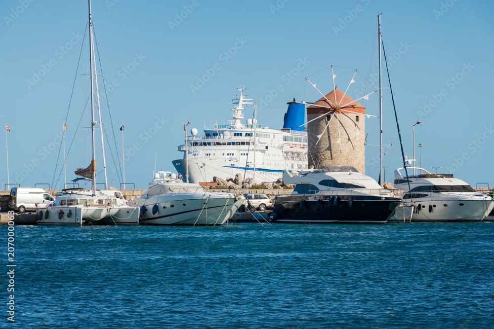 Windmills, boats, yachts and cruise ship in Mandraki harbor in City of Rhodes (Rhodes, Greece)