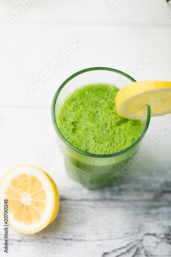 Green cocktail smoothie parsley celery lemon lime slices  healthy drink ingredients  glass of beverage on white wooden table  detox diet clean eating  with vegetables on table