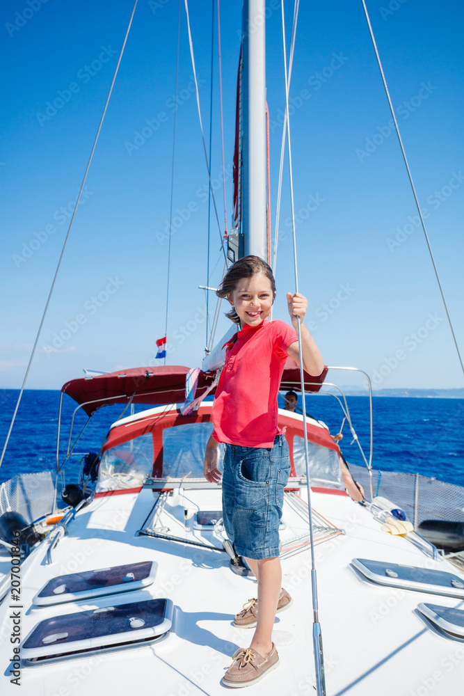 Little boy on board of sailing yacht on summer cruise. Travel adventure, yachting with child on family vacation.