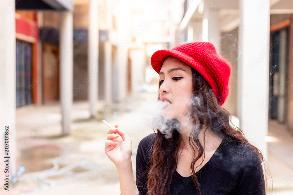 Portrait charming beautiful woman is smoking cigarette and blowing the