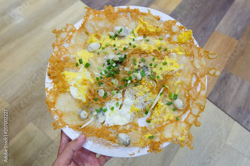 Obraz na plátně Oysters pan-fried crispy in egg batter (Hoi Tod) with bean sprout & spring onion serve on white plate - Homemade Thai-style food background or texture