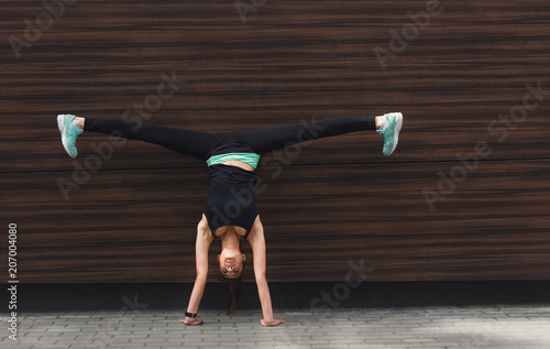 Young woman doing handstand on city street