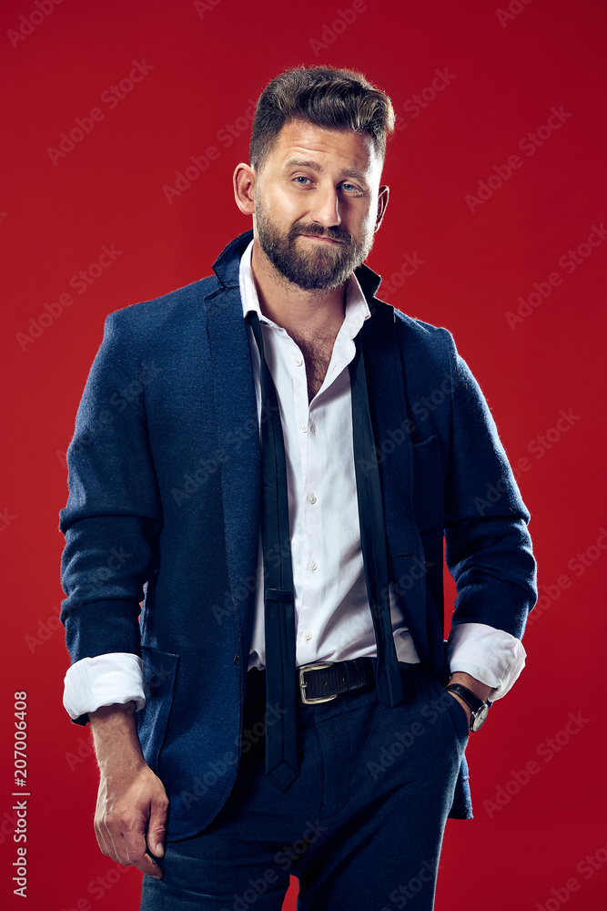The happy business man standing and smiling against red background. The happy business man standing and smiling against red background.