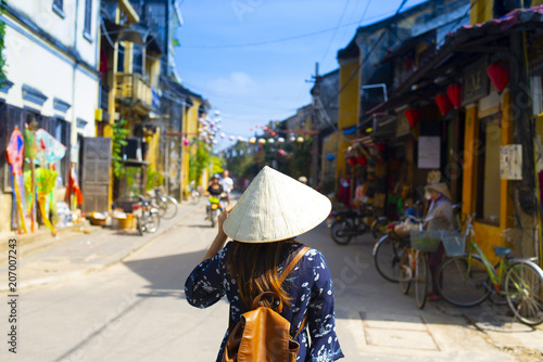Woman tourist is wearing Vietnamese Hat (Non La) and traveling in Hoi An old town in Vietnam.