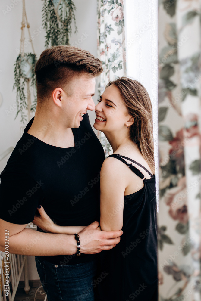 The lovely couple in love embracing near window