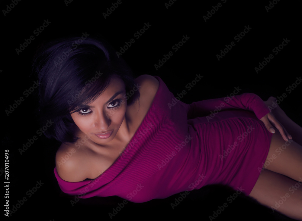 Beautiful exotic young woman wearing sexy dress reclining on bed, Beautiful exotic young woman wearing sexy dress reclining on bed,