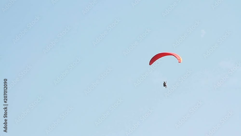 Paragliding over the mountains against clear blue sky Paragliding over the mountains against clear blue sky