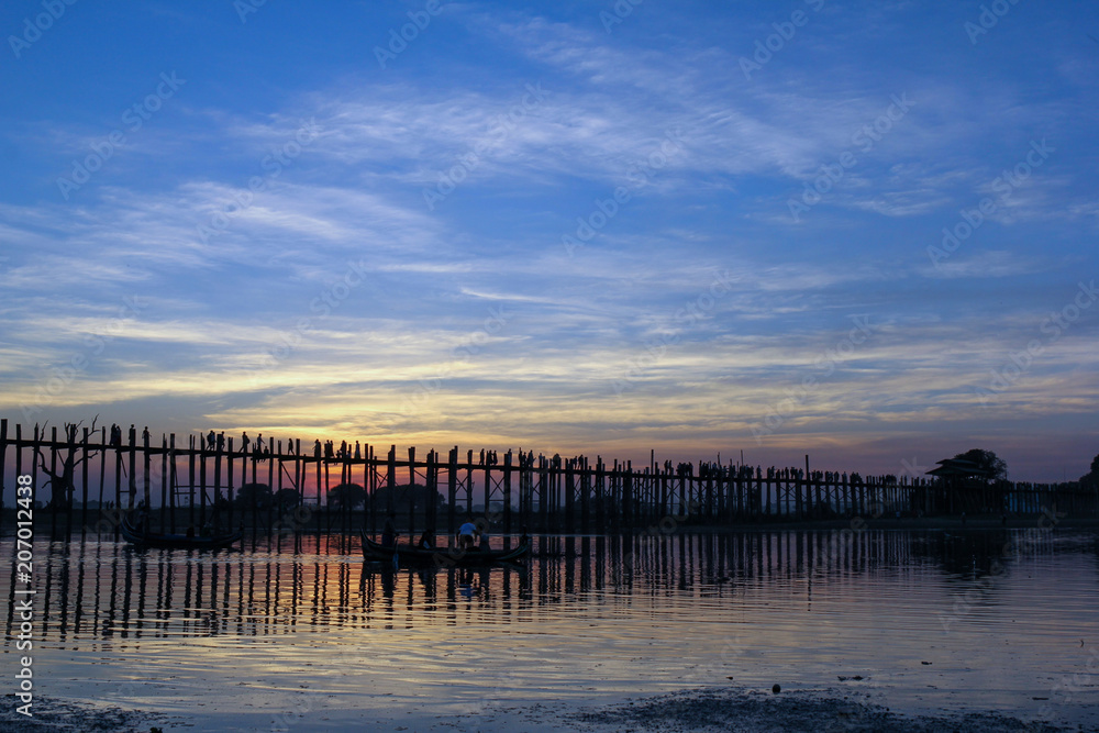 Obraz premium Sunset at the U Bein Bridge at the Taungthaman Lake near Amarapura, Myanmar. The bridge, built around 1850, 1.2 km long, is the longest teakwood bridge in the world.