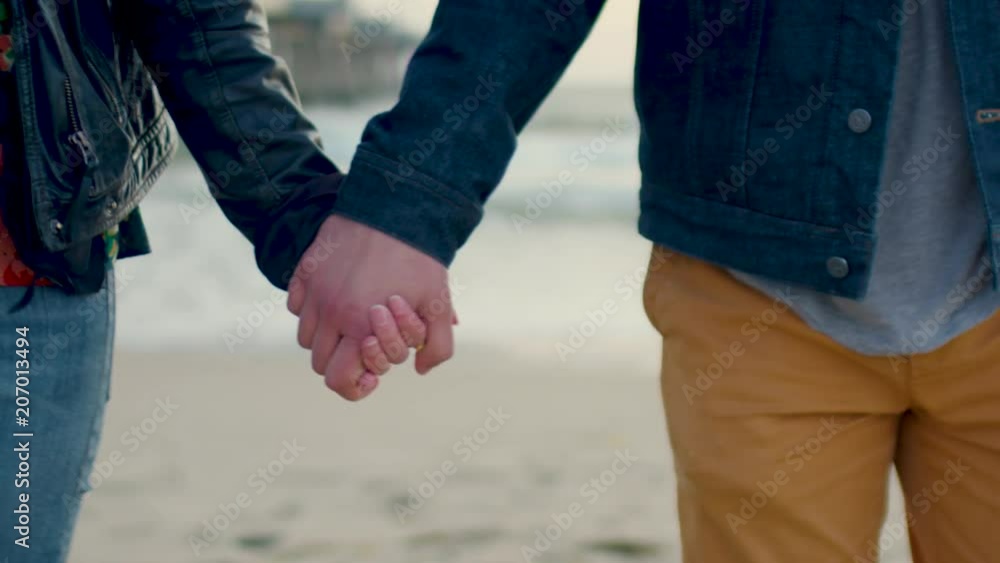 Closeup Of Couple Holding Hands And Walking On Beach At Sunset (Slow Motion) Closeup Of Couple Holding Hands And Walking On Beach At Sunset (Slow Motion)