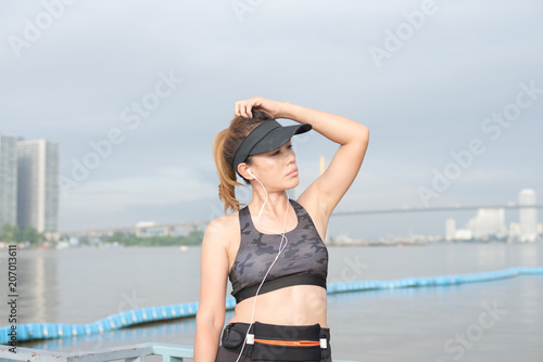 Sporty Woman listening to music with earphones in city © NIPATHORN