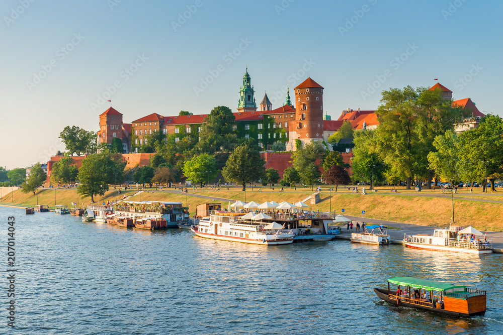 Obraz premium Krakow, Poland - August 11, 2017: panoramic view of the famous Wawel Castle, located on a hill, boats in the Wisla River