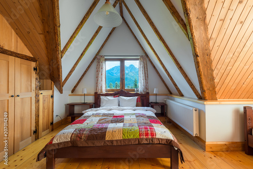 Obraz na płótnie bedroom interior in a wooden house with a beautiful view from the window to the mountains w salonie