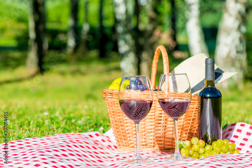 Fototapeta Naklejka Na Ścianę i Meble -  Grapes and wine, basket on a tablecloth in the park - objects for a picnic