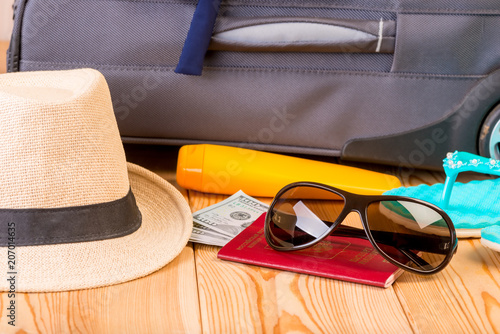 accessories and necessary documents for travel on the background of a gray suitcase on a wooden floor close-up