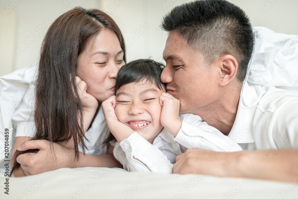 Asian Parents kissing their little son on both cheeks. Asian Parents kissing their little son on both cheeks.
