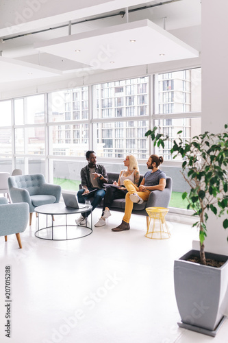 three adults having buisness meeting in big office