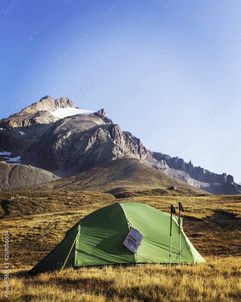 The tent is on top of the mountain. The solar panel hangs on the tent.