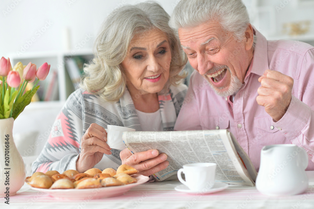senior couple with newspaper  at home 