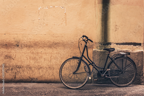 Old bicycle against yellow wall with copy space, toned.