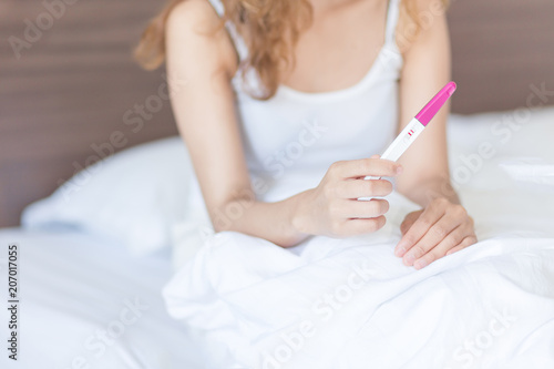 Selective focus Pregnancy test positive result on hand of young woman in her bedroom,Blurred background.