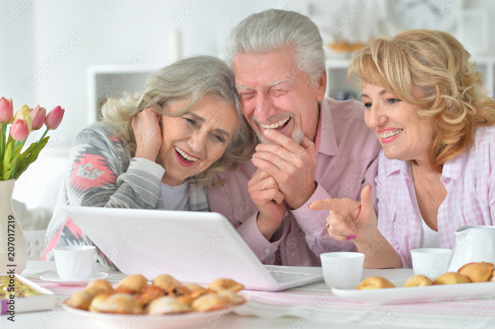 happy senior people with laptop drinking tea