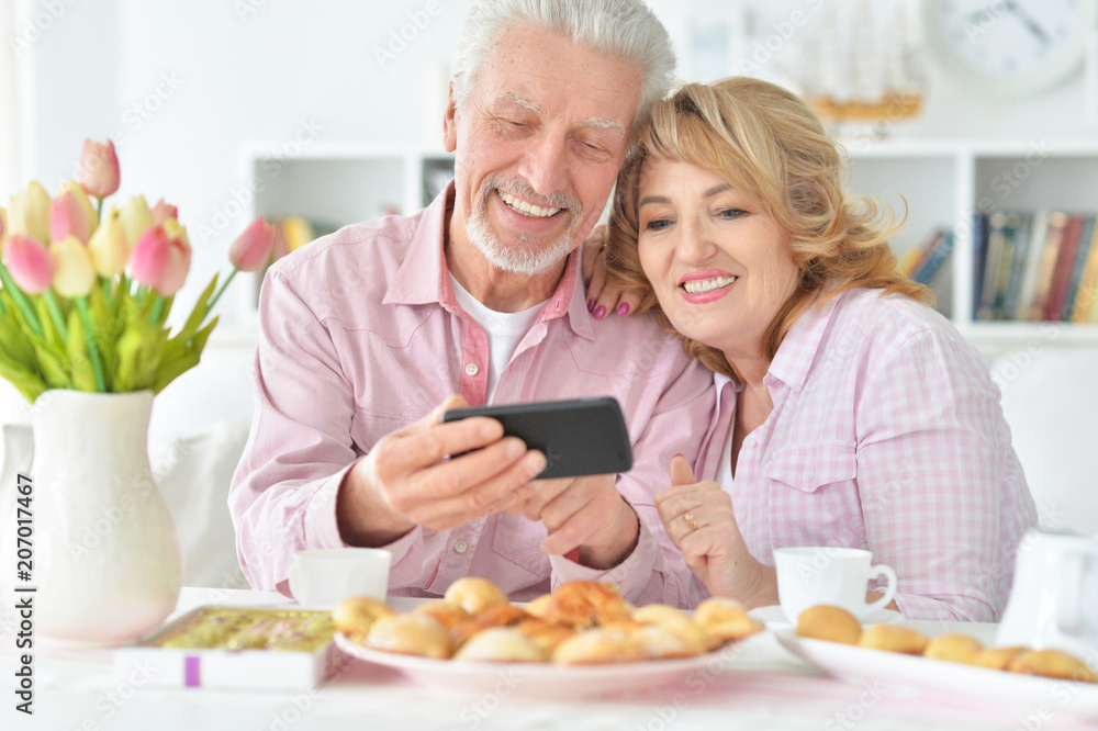senior couple with smartphone drinking tea senior couple with smartphone drinking tea