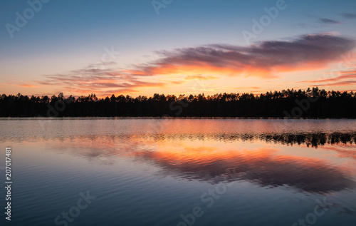 Scenic lake view with reflections and sunset at peaceful evening in National Park Finland
