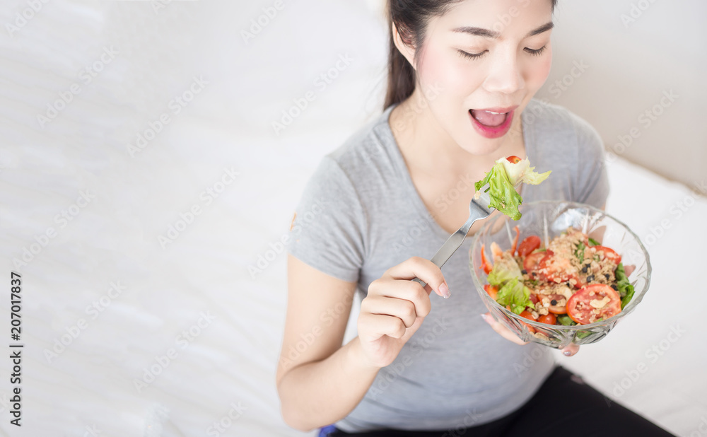 Enjoyed Asian woman eating vegetable salad. Enjoyed Asian woman eating vegetable salad.