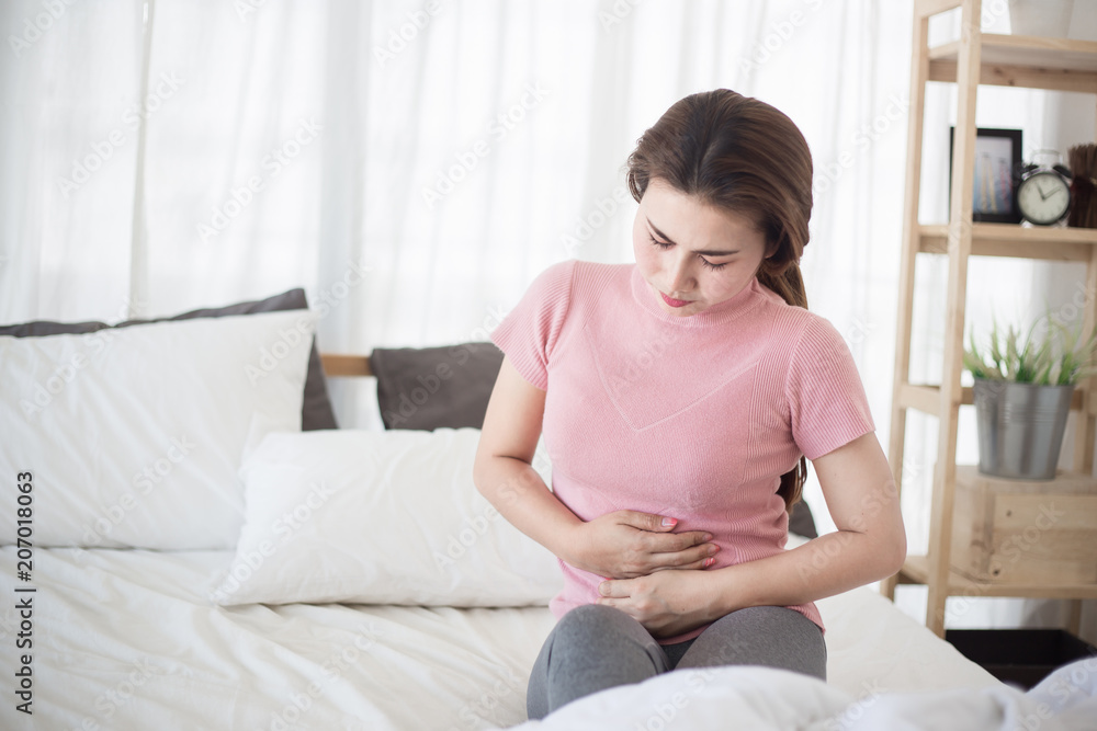 Young asian woman suffering from abdominal pain on the bed. Young asian woman suffering from abdominal pain on the bed.