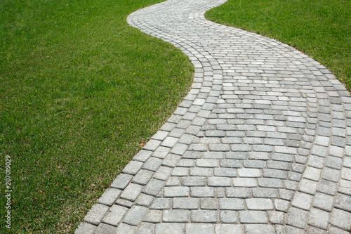 Curved path in the shape of a wave on the grass in the Park. Paved with tiles of different shapes.