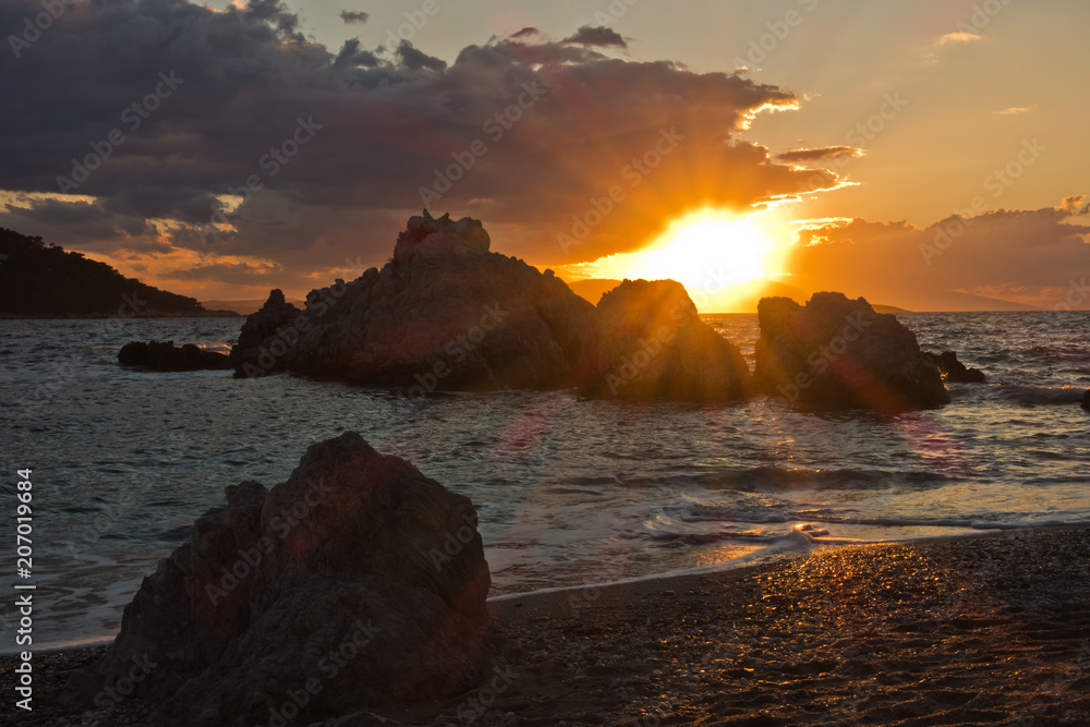 Sea rocks with dramatic clouds at sunset , Kastani Mamma Mia beach, island of Skopelos, Greece