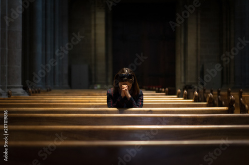 A Christian girl is sitting and praying with broken heart in the church.