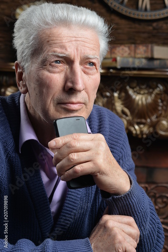 thoughtful senior man with smartphone
