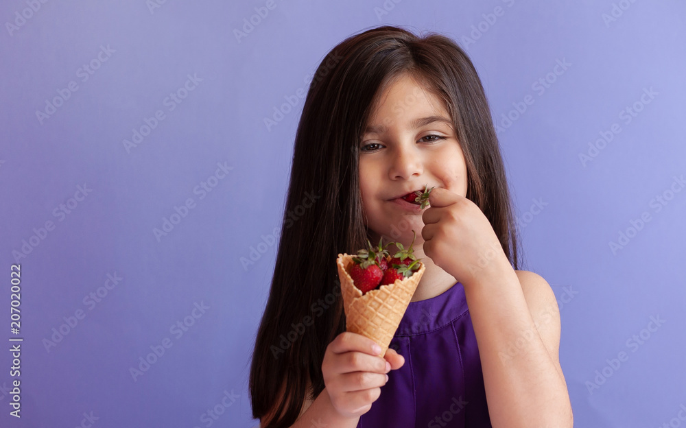 Cute little child girl eating fresh strawberries from ice cream horn. Healthy food. Summer time. Cute little child girl eating fresh strawberries from ice cream horn. Healthy food. Summer time.