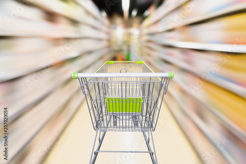 empty shopping cart with blur supermarket aisle with baby formula milk product on the shelf, motion blur