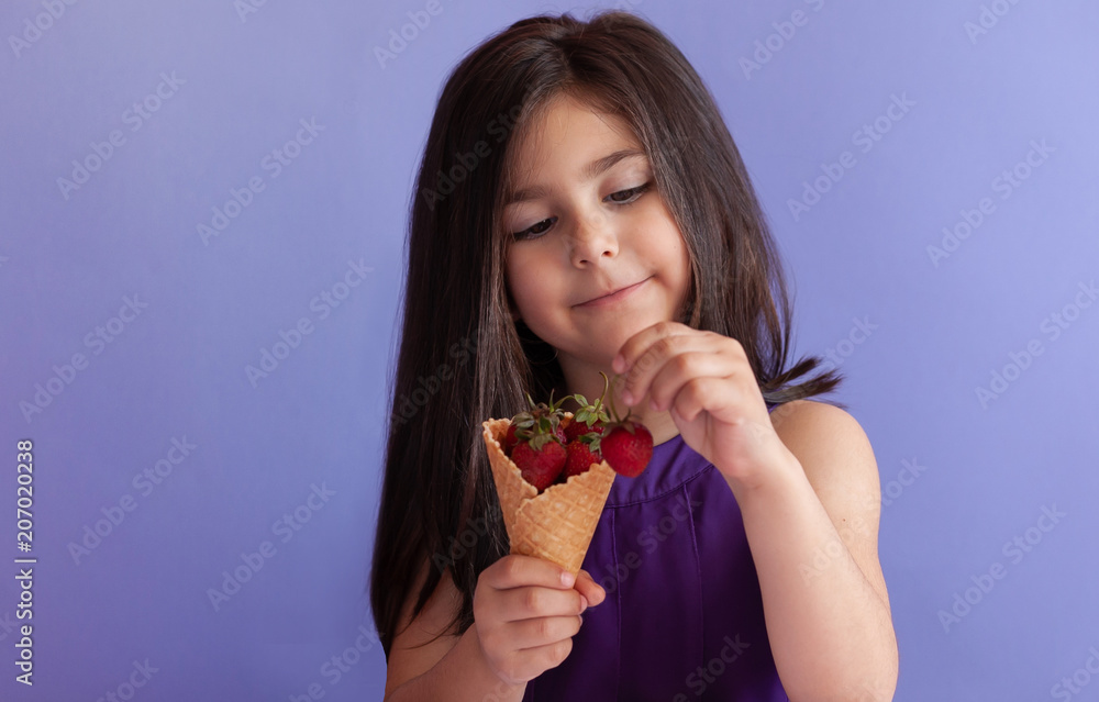 Cute little child girl eating fresh strawberries from ice cream horn. Healthy food. Summer time. Cute little child girl eating fresh strawberries from ice cream horn. Healthy food. Summer time.