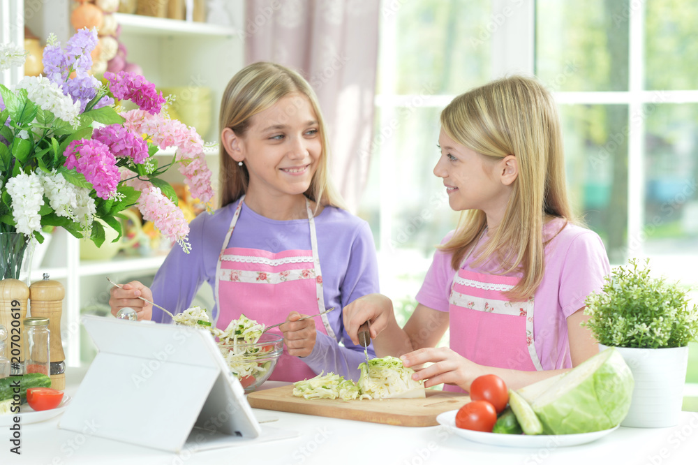 Two girls in aprons preparing fresh salad