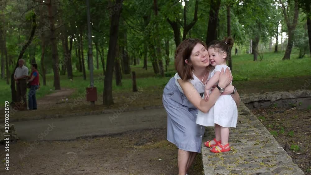 Mom kisses her baby girl in a green park Mom kisses her baby girl in a green park
