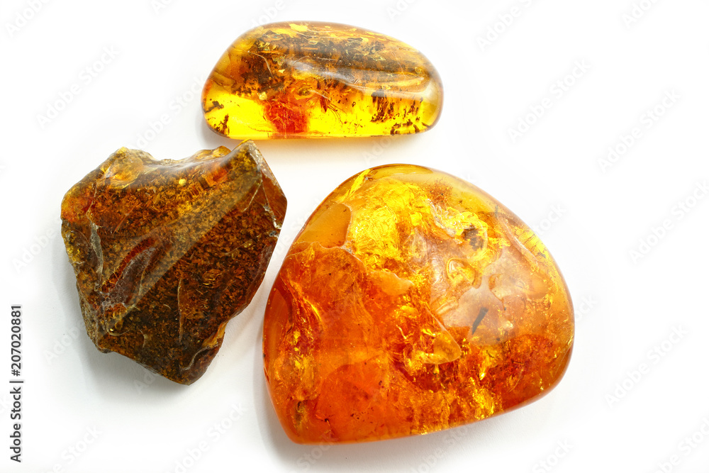 Amber. Three transparent bright red yellow amber pieces on a white background. Ancient fossil resin with Bokeh effect. Material for jewelry. Sunstone with mosquito inside. Insects in pitch. Top view Amber. Three transparent bright red yellow amber pieces on a white background. Ancient fossil resin with Bokeh effect. Material for jewelry. Sunstone with mosquito inside. Insects in pitch. Top view