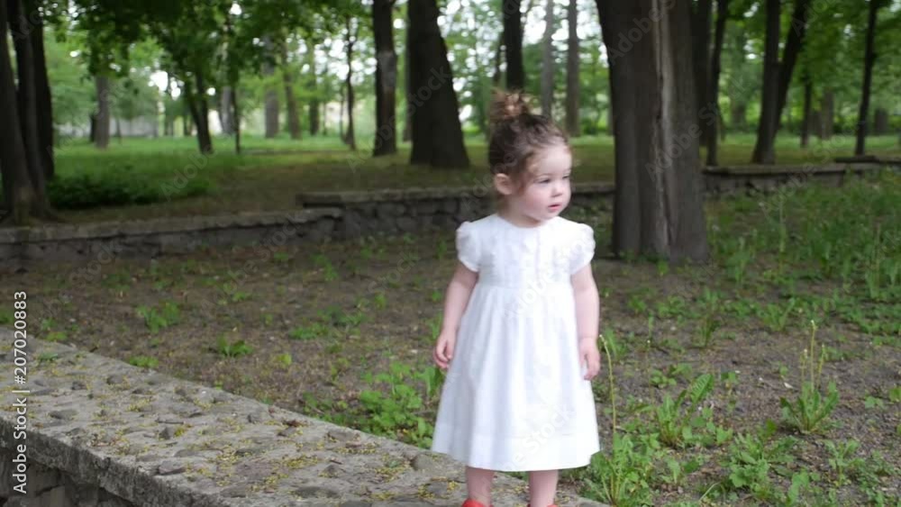 A little girl walks in a green park with her mother A little girl walks in a green park with her mother