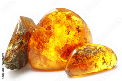 Three bright pieces of amber of different shapes and colors on a white background. Amber texture. A natural mineral for jewelry. Frozen resin with inclusions insects inside. Sun Stone