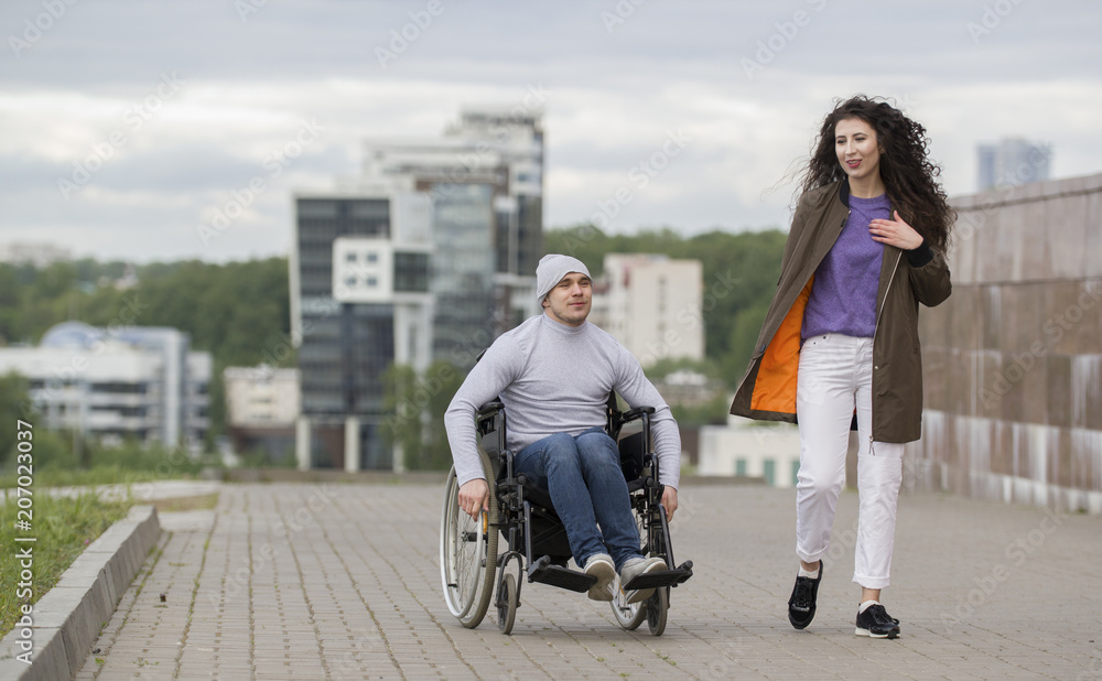 Happy couple - disabled young man in a wheelchair with young woman enjoying the sunset together Happy couple - disabled young man in a wheelchair with young woman enjoying the sunset together